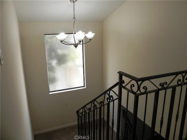 stairway with baseboards and a notable chandelier