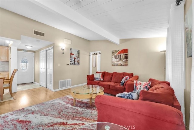 living room featuring vaulted ceiling with beams and light hardwood / wood-style flooring