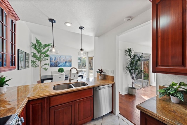 kitchen featuring a sink, light stone countertops, reddish brown cabinets, and stainless steel dishwasher