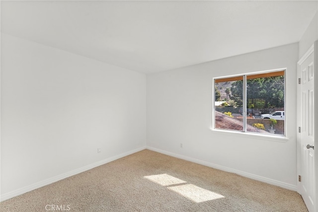 carpeted empty room featuring baseboards