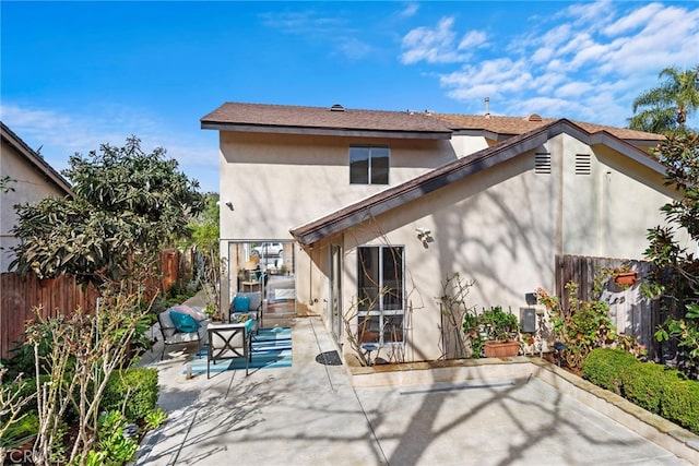 back of house with fence private yard, stucco siding, an outdoor living space, and a patio