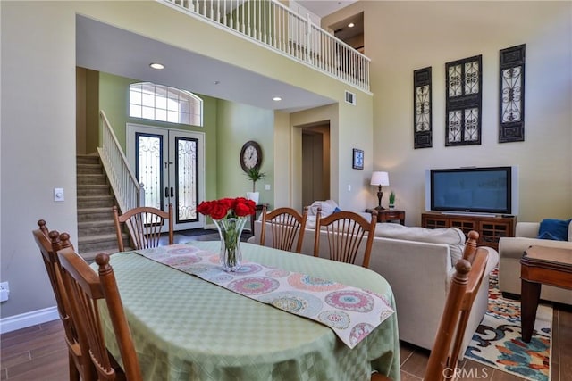 dining area with a high ceiling, french doors, and hardwood / wood-style floors