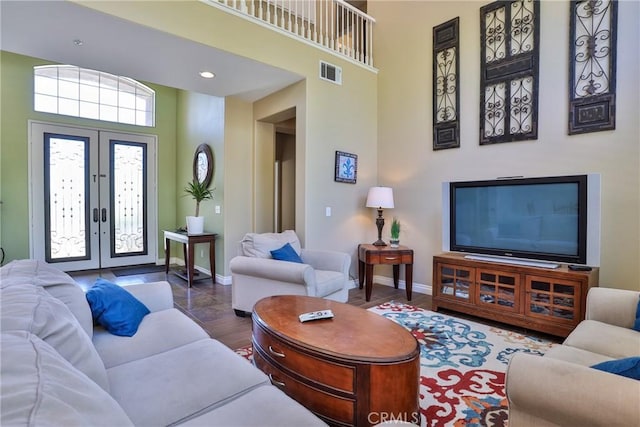 living room featuring hardwood / wood-style flooring, a high ceiling, and french doors