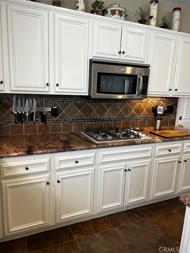 kitchen with white cabinetry, appliances with stainless steel finishes, dark stone counters, and tasteful backsplash