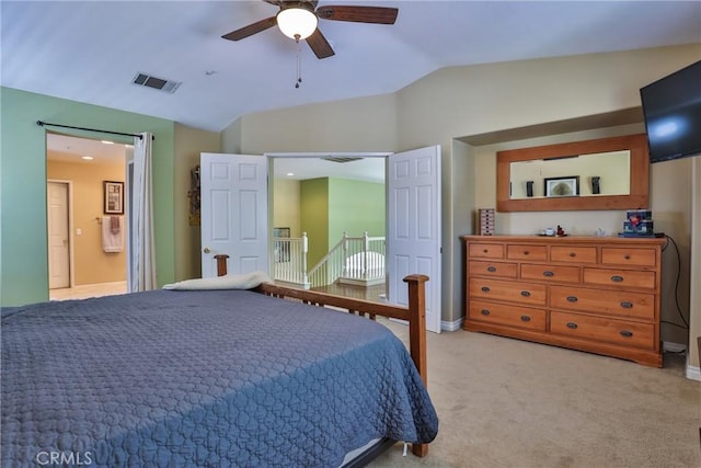 carpeted bedroom with vaulted ceiling, ceiling fan, and ensuite bath