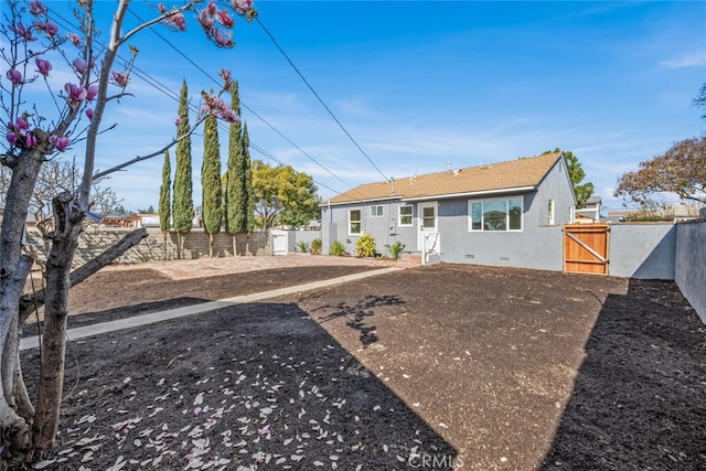 view of front of home with crawl space, a fenced backyard, a gate, and stucco siding