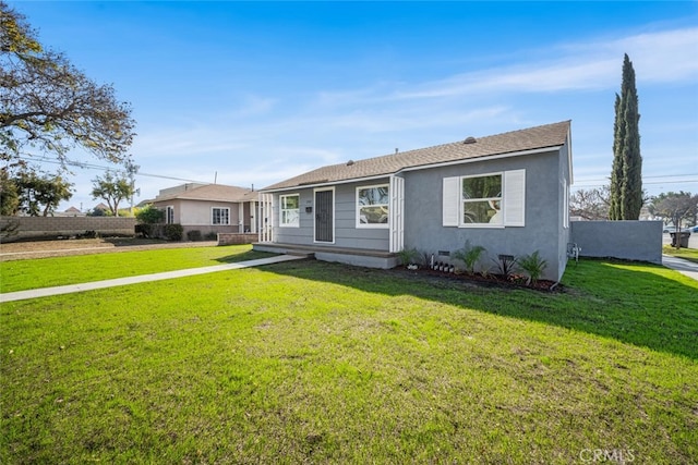 view of front of property with roof with shingles, stucco siding, a front yard, crawl space, and fence