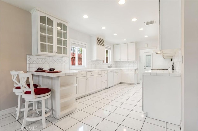 kitchen featuring white cabinetry, tile counters, light tile patterned floors, and decorative backsplash