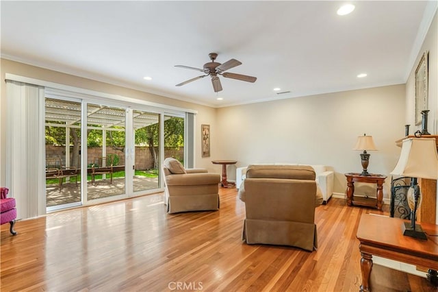 living room with ceiling fan, ornamental molding, and light wood-type flooring