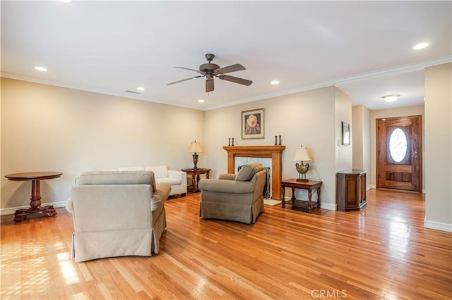 living room featuring light wood-type flooring, ornamental molding, and ceiling fan