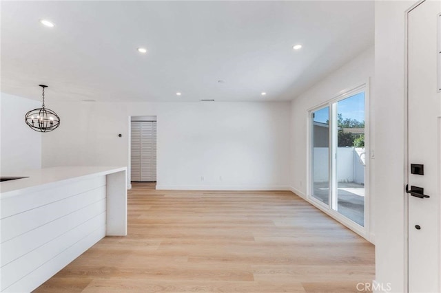 spare room with a notable chandelier and light hardwood / wood-style flooring