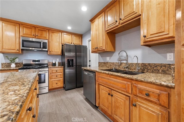 kitchen with recessed lighting, light wood-style flooring, appliances with stainless steel finishes, a sink, and light stone countertops