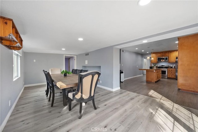 dining room with light wood-style floors, recessed lighting, and baseboards