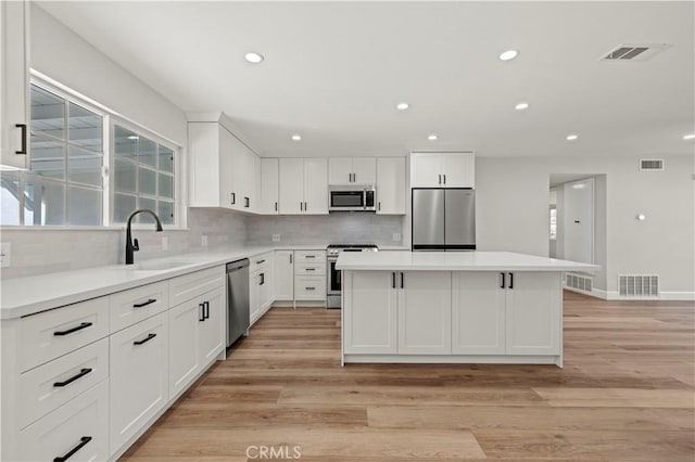 kitchen featuring visible vents, stainless steel appliances, light countertops, white cabinetry, and a sink