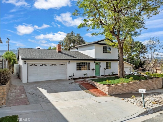 traditional-style house featuring a garage, driveway, roof with shingles, and stucco siding