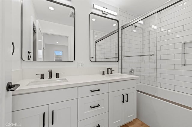 bathroom with double vanity, visible vents, combined bath / shower with glass door, and a sink