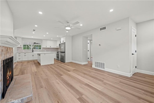 unfurnished living room featuring light wood-type flooring, visible vents, a fireplace, and recessed lighting