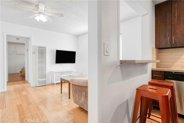 kitchen featuring dark brown cabinetry, a textured ceiling, light wood-style flooring, and stainless steel dishwasher