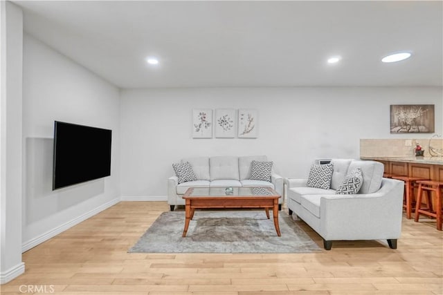 living area with baseboards, light wood-style flooring, and recessed lighting
