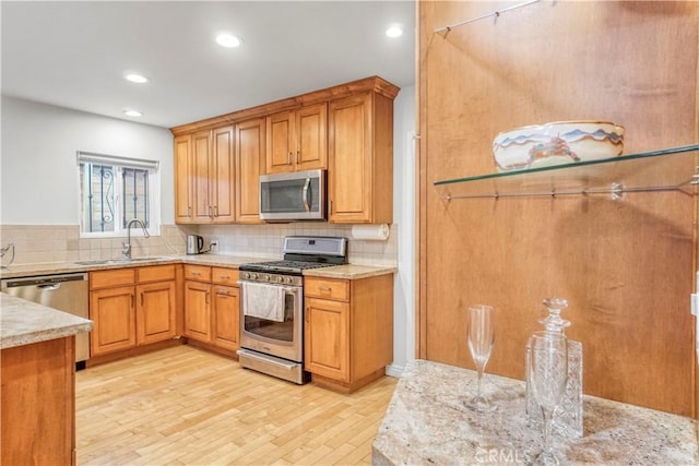 kitchen featuring light wood finished floors, a sink, stainless steel appliances, backsplash, and recessed lighting