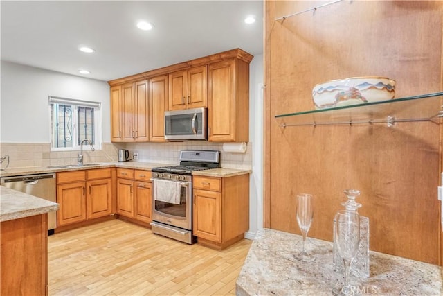 kitchen with stainless steel appliances, recessed lighting, tasteful backsplash, a sink, and light wood-style floors