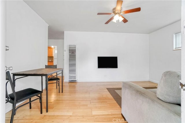 living room featuring baseboards, ceiling fan, and light wood-style floors