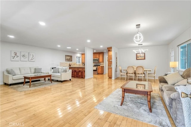living area featuring light wood finished floors, baseboards, recessed lighting, and an inviting chandelier