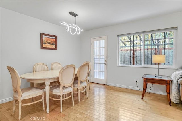 dining space with baseboards, a notable chandelier, and light wood-style floors