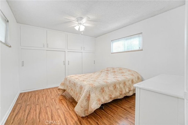 bedroom featuring a closet, a textured ceiling, a ceiling fan, and light wood finished floors