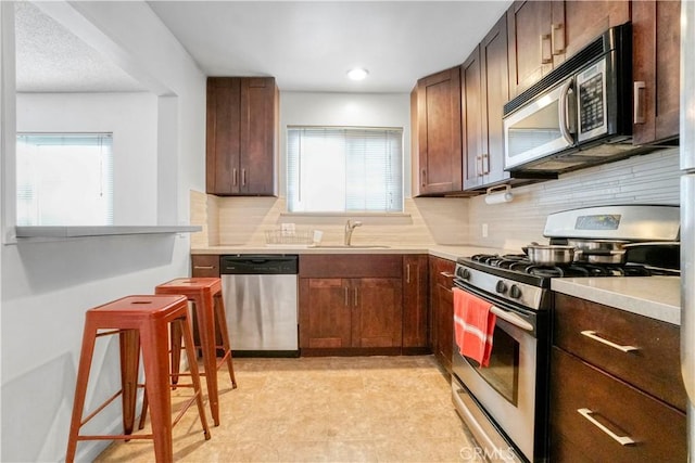 kitchen featuring decorative backsplash, a wealth of natural light, a sink, and appliances with stainless steel finishes