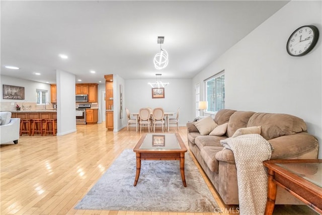 living room with light wood-type flooring, a notable chandelier, and recessed lighting