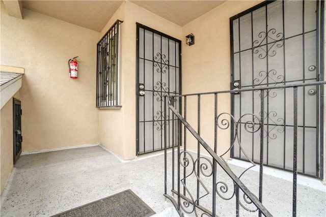 view of exterior entry featuring stucco siding and a gate