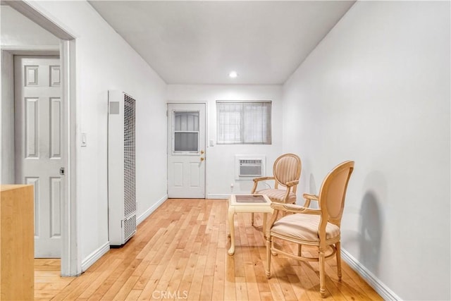 living area with recessed lighting, a heating unit, an AC wall unit, baseboards, and light wood-style floors