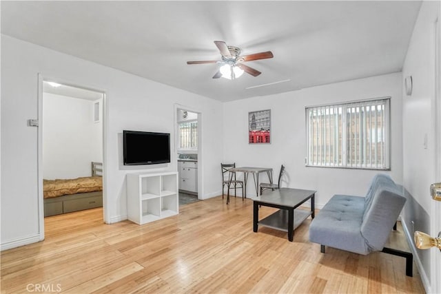 sitting room featuring a healthy amount of sunlight, light wood finished floors, baseboards, and a ceiling fan