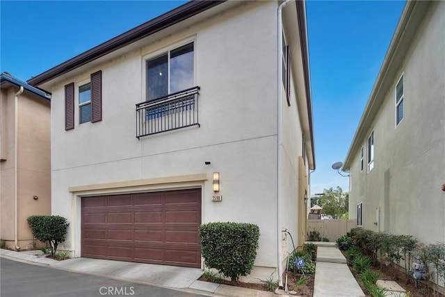 view of front of house with an attached garage, fence, and stucco siding