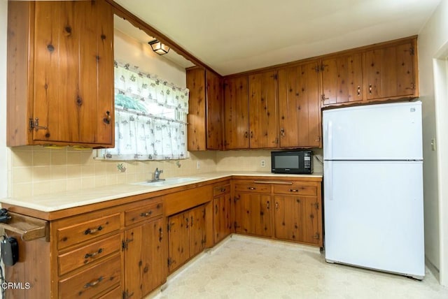 kitchen featuring white fridge, sink, and decorative backsplash