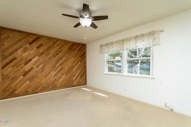 carpeted spare room with ceiling fan and wooden walls