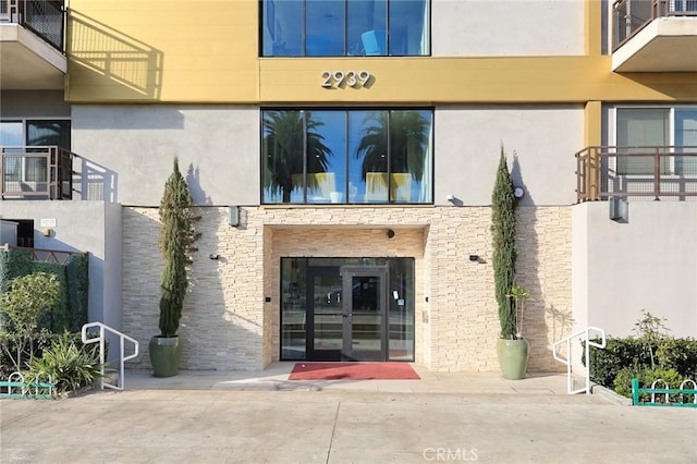 view of exterior entry with stucco siding and stone siding