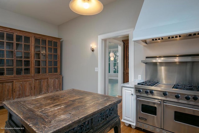 kitchen with light wood finished floors, range with two ovens, custom exhaust hood, and butcher block counters