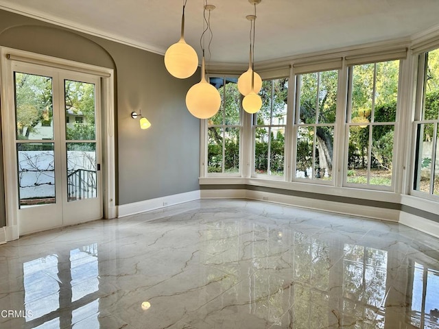 unfurnished dining area featuring marble finish floor, baseboards, ornamental molding, and a wealth of natural light