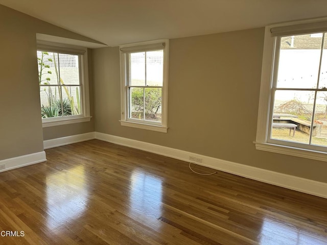 spare room with dark wood-style floors, vaulted ceiling, and baseboards