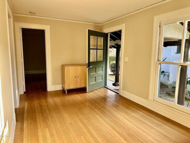 spare room with baseboards, wood finished floors, and ornamental molding