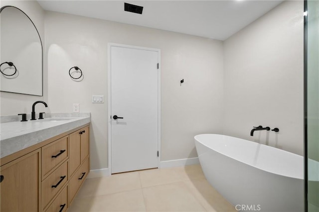 bathroom with a tub to relax in, vanity, and tile patterned flooring