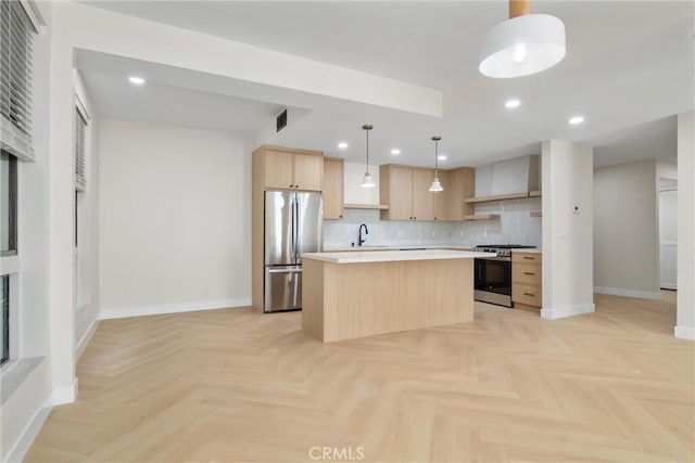 kitchen with hanging light fixtures, a kitchen island, appliances with stainless steel finishes, wall chimney range hood, and light brown cabinetry