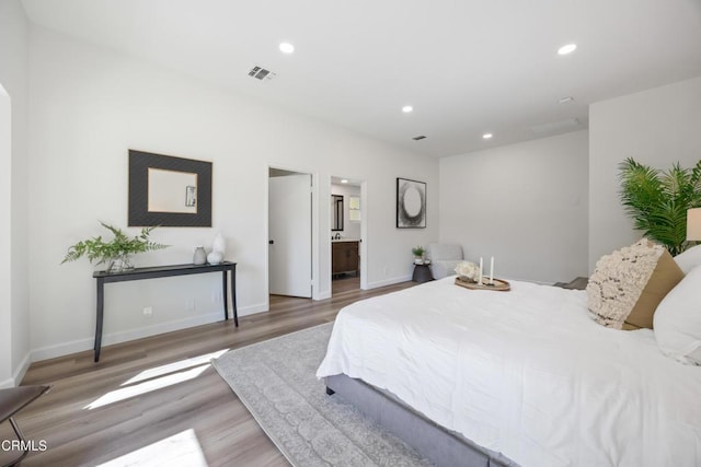 bedroom with ensuite bath and wood-type flooring