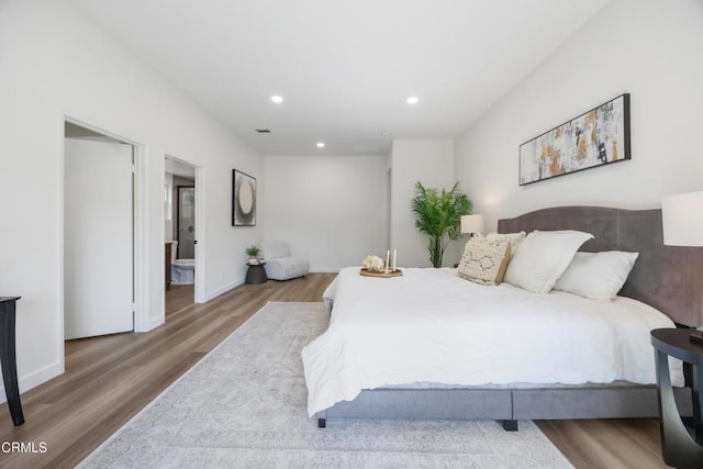 bedroom featuring ensuite bath and wood-type flooring