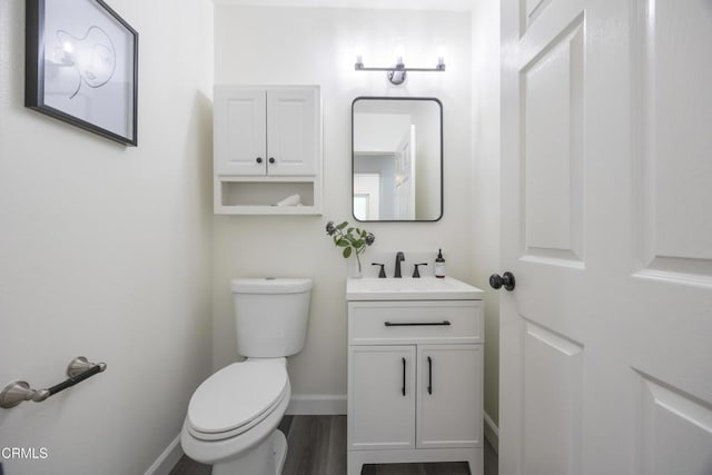 bathroom with wood-type flooring, vanity, and toilet