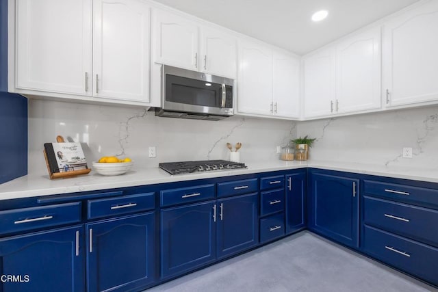 kitchen with white cabinetry, blue cabinetry, tasteful backsplash, and stainless steel appliances