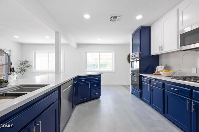 kitchen with appliances with stainless steel finishes, white cabinets, blue cabinets, backsplash, and sink