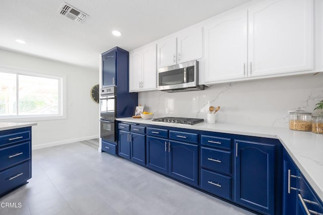 kitchen with appliances with stainless steel finishes, blue cabinets, and decorative backsplash